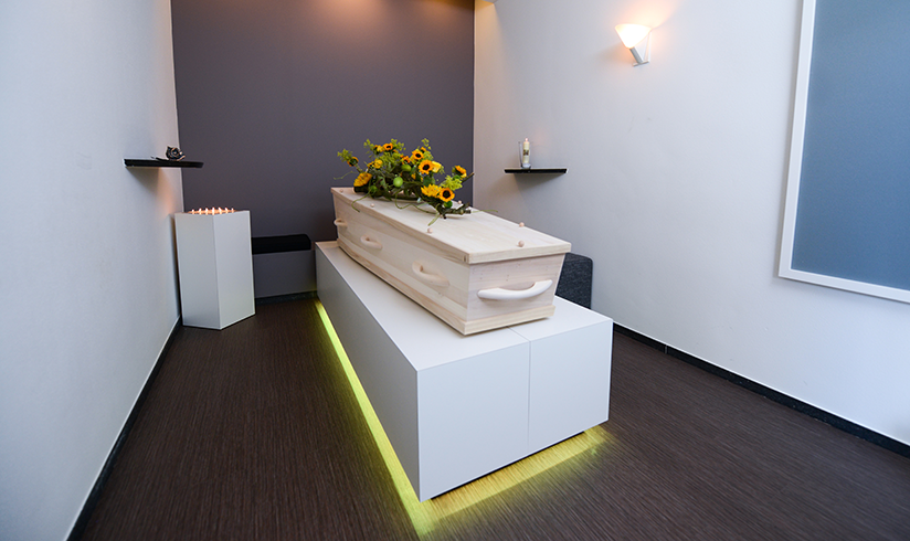 Kleine kamer met een uitvaartkist met bloemen